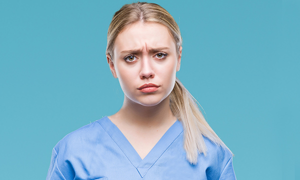A worried-looking nursing student wearing scrubs