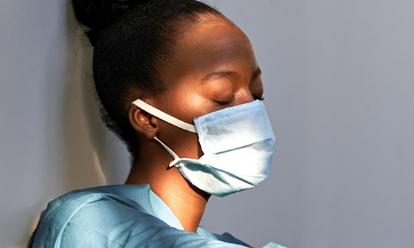 Picture shows a young woman medic with her eyes closed and looking tired