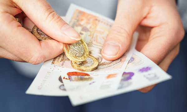 Pay rates: a hand holding pound coins and ten pound notes