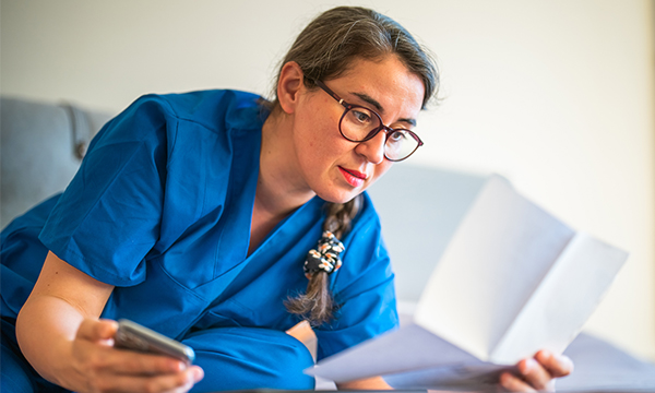 A nurse studying a document while holding a calculator in her other hand