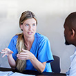 Young female doctor talking with a diverse team of medical professionals during a meeting around a conference table in a hospital