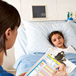 Doctor Using Digital Notepad Whilst Visiting Child Patient Smiling