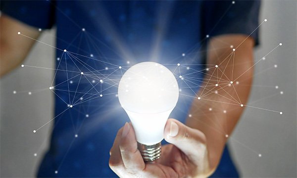 Nurse led-innovation: nurse holds light bulb with dots joined by lines illustrated as emanating from it
