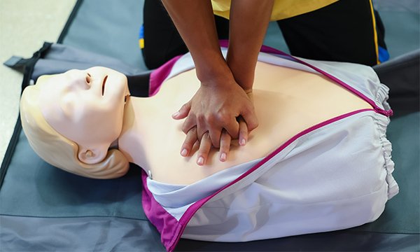 A person undertakes CPR training on an adult manikin