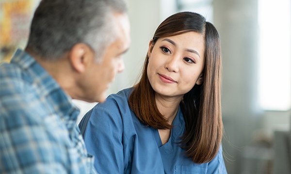 Active listening in nursing: nurse sitting with a service user, making eye contact as he talks